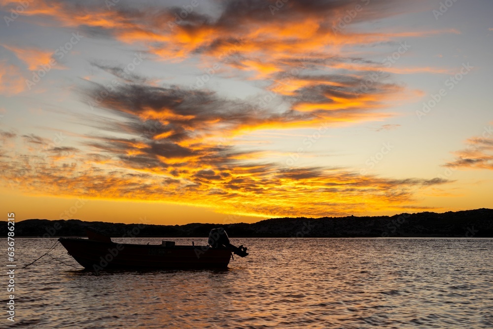 Small boat sailing down a body of water at sunset in Kalbarri, Australia. Small boat sailing down a body of water at sunset in Kalbarri, Australia.
