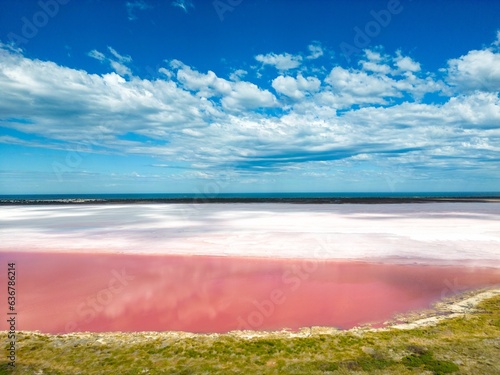 Scenic view of Pink Lake in Kalbarri, Port Gregory, Australia under a cloudy blue sky photo