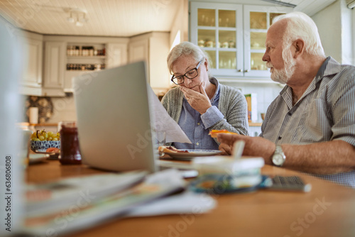 Senior couple going over their bills and home finances while having breakfast in the morning