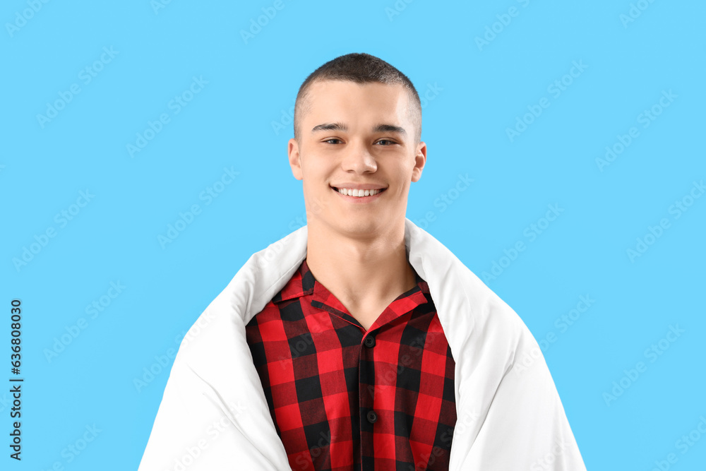 Young man with blanket on blue background Young man with blanket on blue background