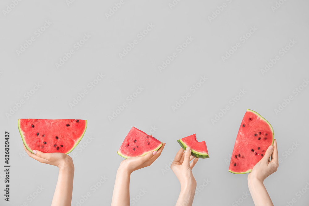 Female hands with pieces of ripe watermelon on light grey background Female hands with pieces of ripe watermelon on light grey background