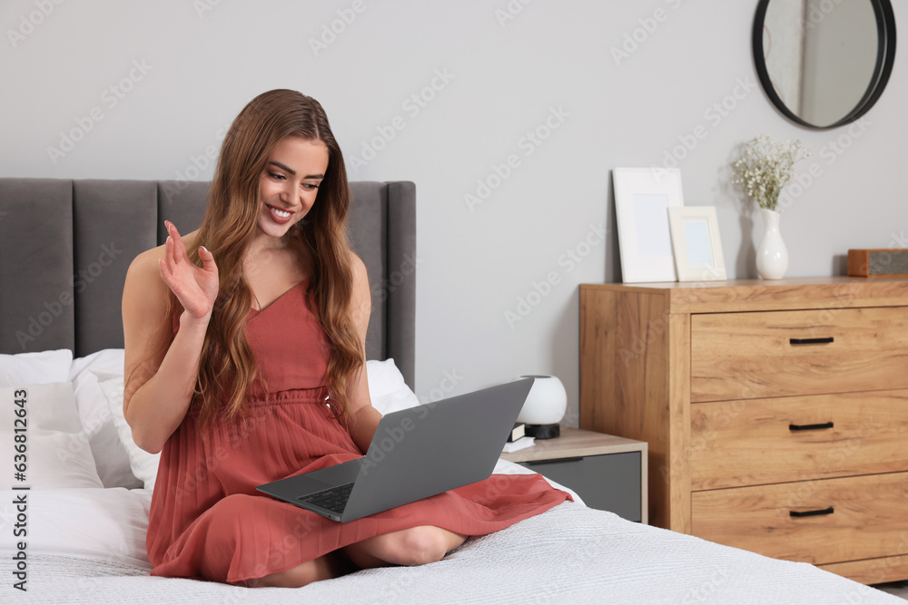 Happy woman having video chat via laptop on bed in bedroom Happy woman having video chat via laptop on bed in bedroom