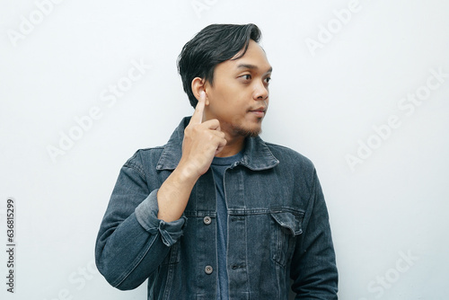 Portrait of Indonesian Asian man point his index finger on ear showing deafness gesture. Isolated white background photo