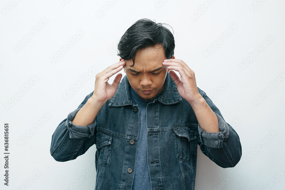 Portrait of an Asian Indonesian man put his hands on head for headache gesture. Isolated white background Portrait of an Asian Indonesian man put his hands on head for headache gesture. Isolated white background