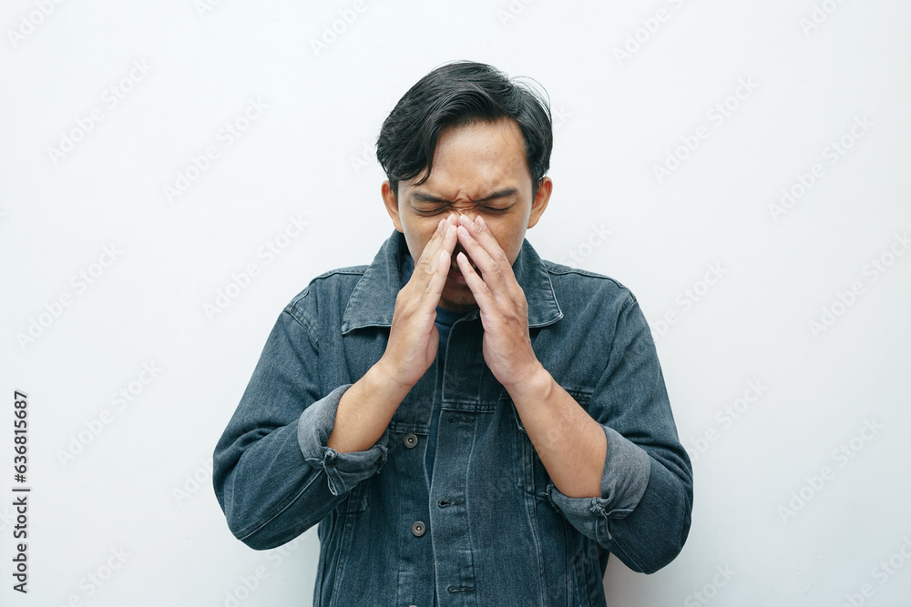 Portrait of Indonesian Asian man sneezing gesture. Unhealthy sick concept isolated white background Portrait of Indonesian Asian man sneezing gesture. Unhealthy sick concept isolated white background