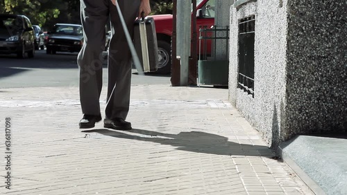 Blind Man with Cane Walking on A Sidewalk in Buenos Aires, Argentina. Low Angle View. 4K Resolution. photo