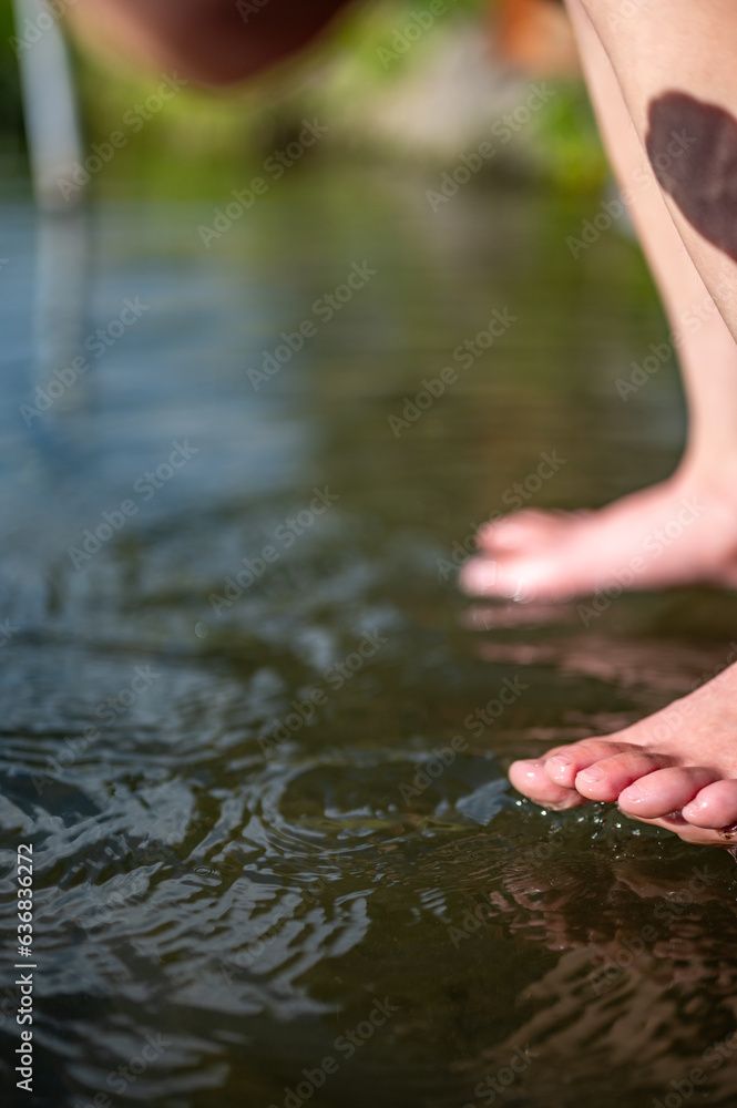 Fototapeta premium Caucasian child dipping toes into a cold snowmelt mountain stream on a sunny day
