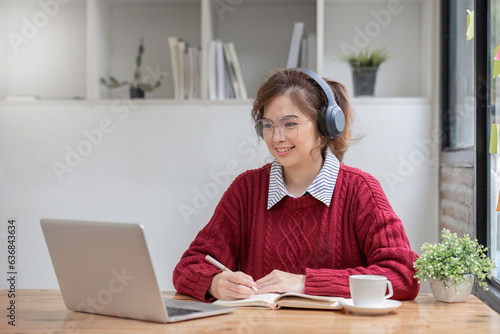 Asian female student study online in class, study online, wearing headphones, watching video call, zooming, happy asian female learning language online with computer laptop.