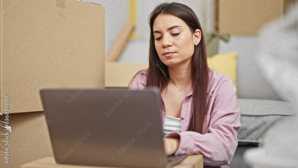 Young beautiful hispanic woman using laptop sitting on floor thinking at new home Young beautiful hispanic woman using laptop sitting on floor thinking at new home