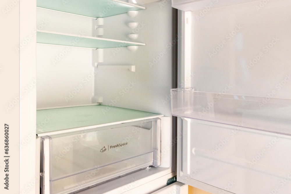 A refrigerator with empty shelves. The concept of lack of food, hunger, poverty A refrigerator with empty shelves. The concept of lack of food, hunger, poverty
