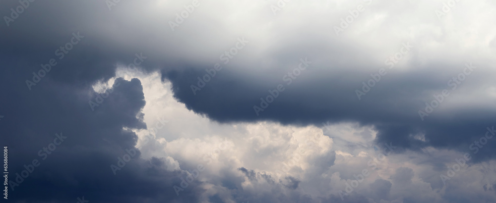 A narrow strip of sky with white clouds is visible through the dark cloud A narrow strip of sky with white clouds is visible through the dark cloud