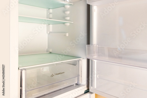 A refrigerator with empty shelves. The concept of lack of food, hunger, poverty