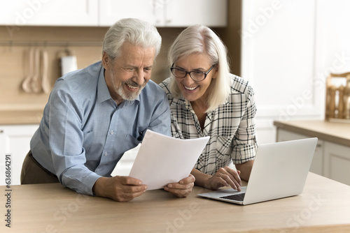 Happy satisfied senior retired couple reading legal document, financial report, paper insurance agreement, getting good news, investment income, enjoying good successful retirement