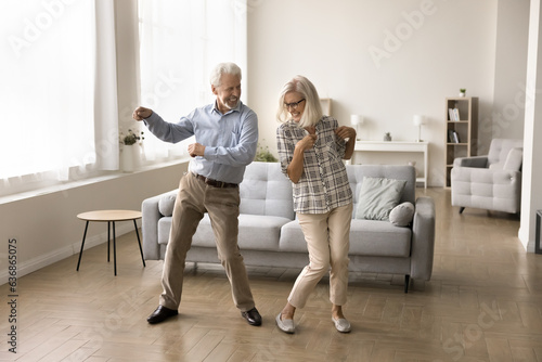 Papier peint Cheerful active retired elder dancing to disco music in spacious living room, ha