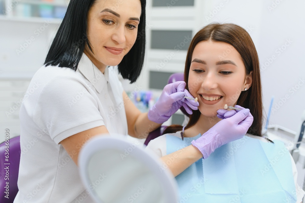 Young woman choosing color of teeth at dentist