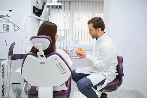 Doctor shows on a plastic tooth sample or model different methods of teeth treatment