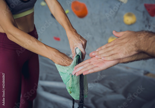 A couple of climbers use talc befor climbing an artificial wall with colorful grips and ropes.