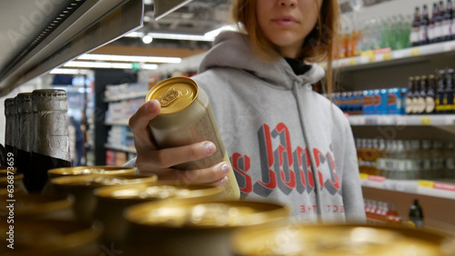 Cuadro en lienzo Close-up of a cute girl's hand taking a golden can of beer in a supermarket