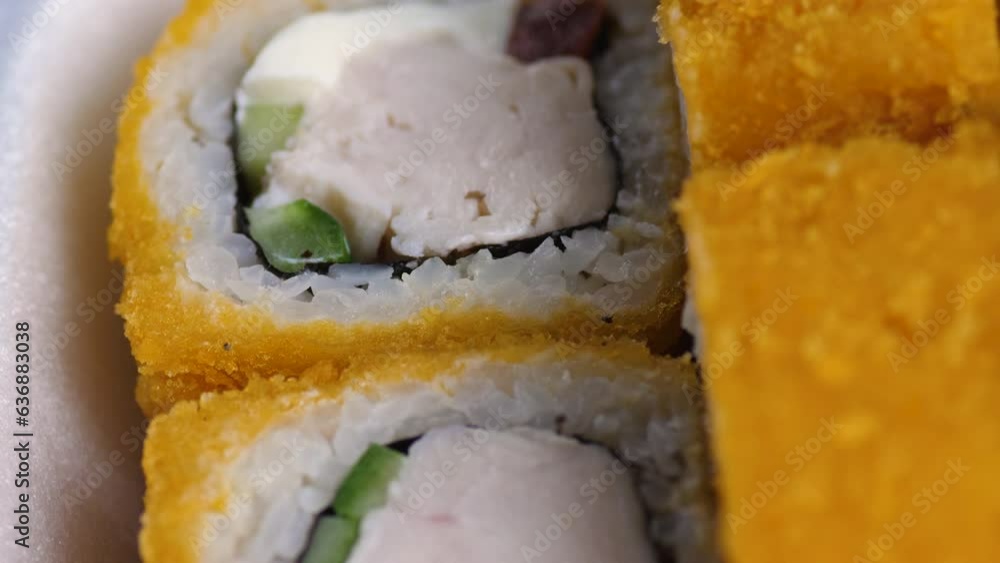 close-up set of baked appetizing sushi in a plastic container for delivery rotation. sushi with rice , fish , fried cucumber .sushi macro close-up set of baked appetizing sushi in a plastic container for delivery rotation. sushi with rice , fish , fried cucumber .sushi macro