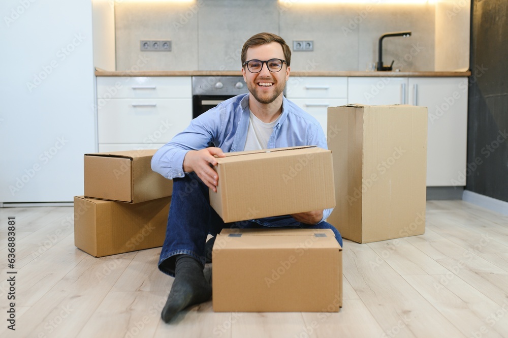 Young caucasian man at a new home with cardboard boxes Young caucasian man at a new home with cardboard boxes