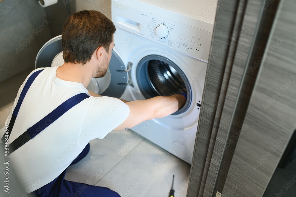 working man plumber repairs a washing machine working man plumber repairs a washing machine