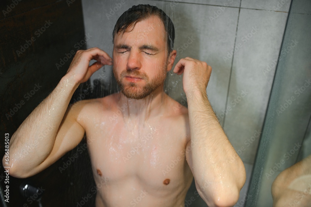 Relaxing after stressful day. Waist up portrait of naked muscular gentleman taking shower at home. Relaxing after stressful day. Waist up portrait of naked muscular gentleman taking shower at home.