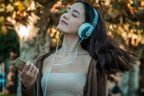 young woman with headphones relaxed in autumnal background photo