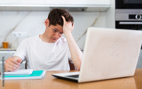 Young guy studying at home with laptop