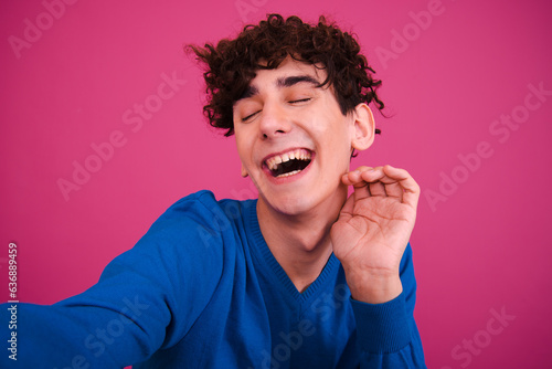 Attractive guy posing on a pink background. The student is happy and sad.