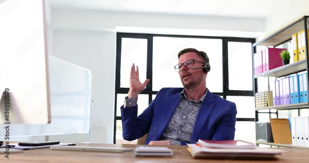 Man top executive wearing headset at online meeting with colleagues via computer. Businessman CEO during conference at computer in office Man top executive wearing headset at online meeting with colleagues via computer. Businessman CEO during conference at computer in office