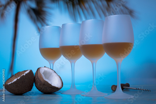 White wine in wine glasses on background of tropical beach and palma with coconut