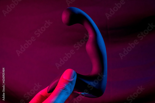 Man holding prostate stimulator in pink neon light. photo