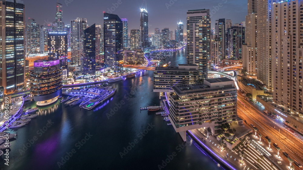 Fototapeta premium Aerial view to Dubai marina skyscrapers around canal with floating boats day to night timelapse