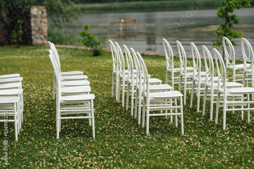 Chairs set up by the green lawn in preparation for a wedding reception © ruslan_shramko