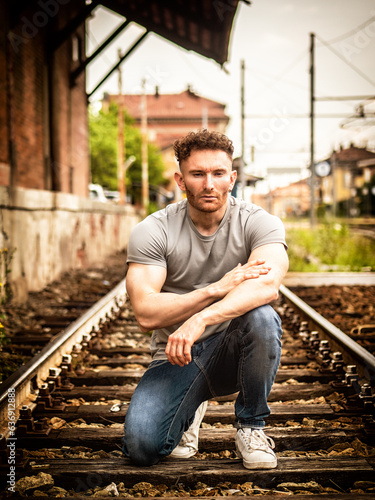 Photo of a man sitting on train tracks with a defiant pose