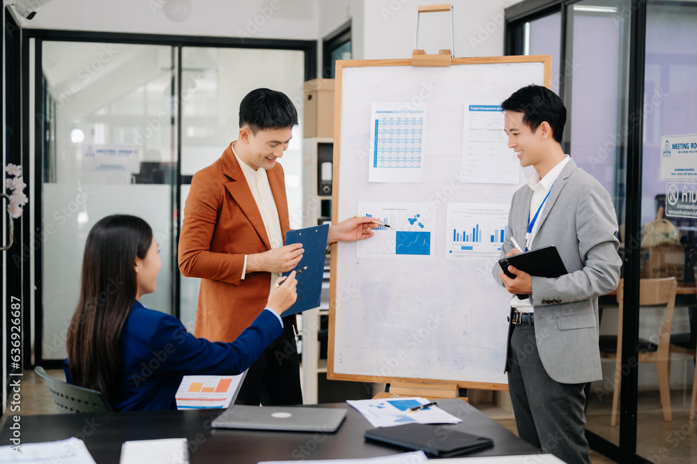 Group of young Asian business people discussing business plan at modern startup in creative business discussing work modern office building.