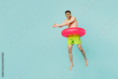 Full body side view young sexy man wear green shorts swimsuit mask for scuba diving relax near hotel pool jump into water isolated on plain blue background. Summer vacation sea rest sun tan concept. photo