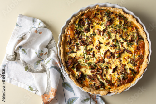 Homemade quiche with seasonal forest mushrooms Chanterelles in a round shape on a yellow background photo