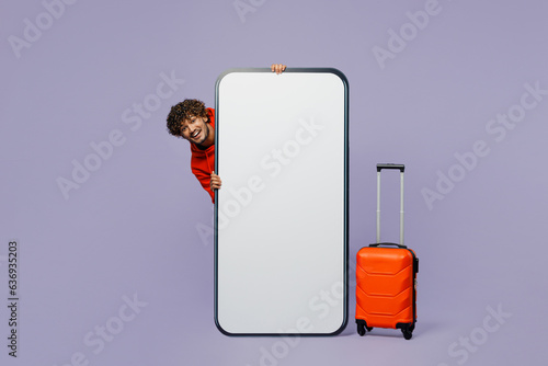 Traveler young Indian man hold bag big huge blank screen mobile cell phone isolated on plain purple background. Tourist travel abroad in free spare time rest getaway. Air flight trip journey concept. #636935203