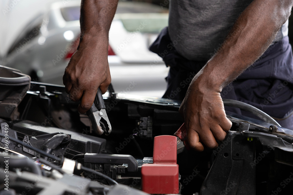 close up mechanic worker hands holding battery cable for jumping battery of a car in automobile repair shop close up mechanic worker hands holding battery cable for jumping battery of a car in automobile repair shop