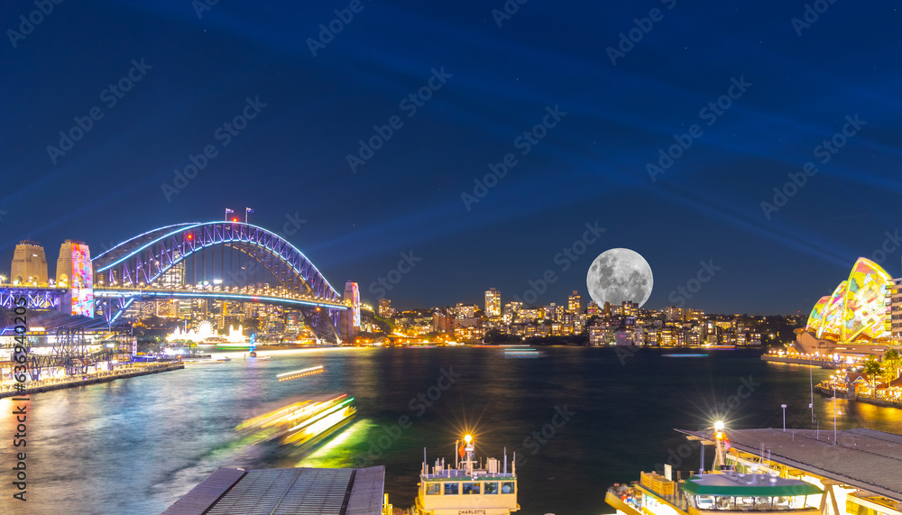 Panoramic night view of Sydney Harbour and City Skyline with a Sturgeon full Moon NSW Australia bright neon lights reflecting off the water