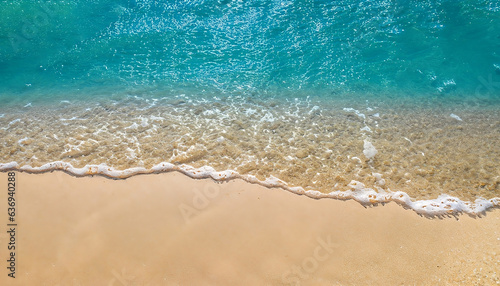 Top view of a calm beach scene featuring the motion of the blue sea and waves on the ocean's shoreline
