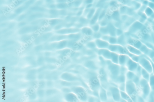 Blue water with ripples on the surface. Defocus blurred transparent blue colored clear calm water surface texture with splashes and bubbles. Water waves with shining pattern texture background.