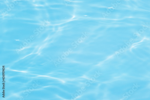 Blue water with ripples on the surface. Defocus blurred transparent blue colored clear calm water surface texture with splashes and bubbles. Water waves with shining pattern texture background.