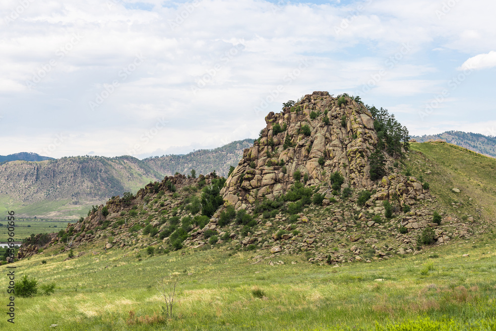 Omulevaya hill (Sleeping Lion Mountain ) near Tarbagatay, Republic of Buryatia, Russia.A huge rock with stone ledges. A smooth slope covered with rare plants. Natural monument.High cliff.