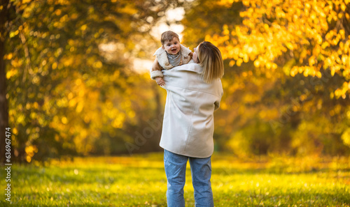 Baby boy with mother in colorful autumn park playing and laughing