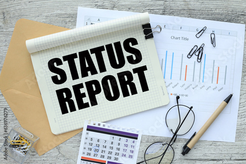 top view of notebook, calendar envelope, financial charts. words STATUS REPORT