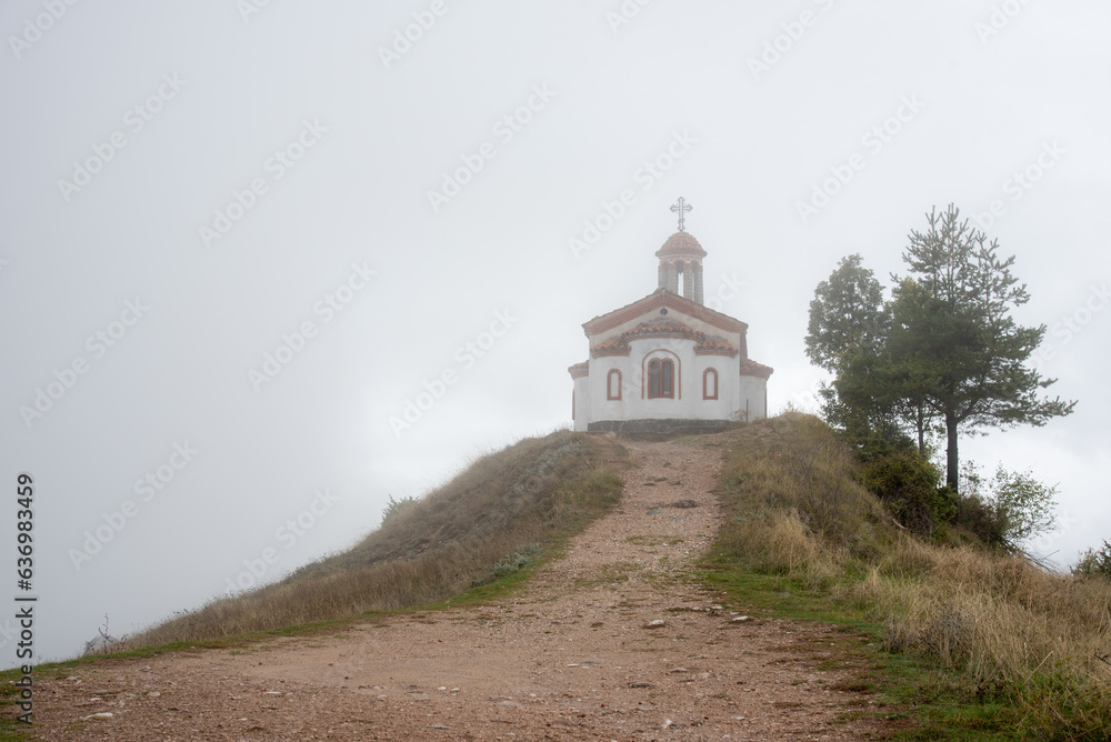 A little chapel on top of a hill in a foggy autumn day A little chapel on top of a hill in a foggy autumn day
