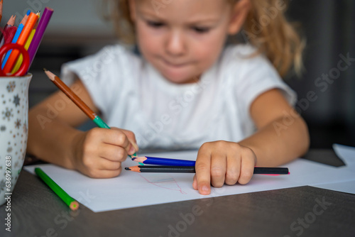 little girl draws with colored pencils in home.  photo