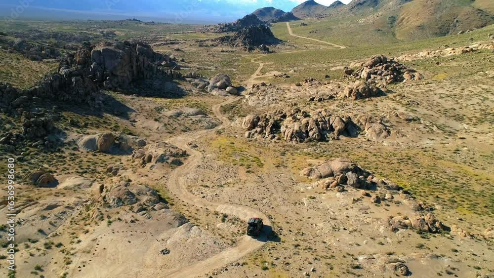 Aerial: Slow Motion Tilt Up Shot Of Vehicle Moving On Dirt Road, Drone Flying Over Landscape - Alabama Hills, California Aerial: Slow Motion Tilt Up Shot Of Vehicle Moving On Dirt Road, Drone Flying Over Landscape - Alabama Hills, California